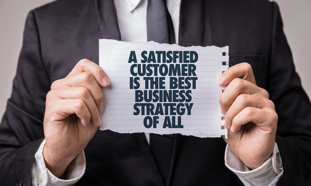 Business owner holding a sign that says a satisfied customer is the best business strategy
