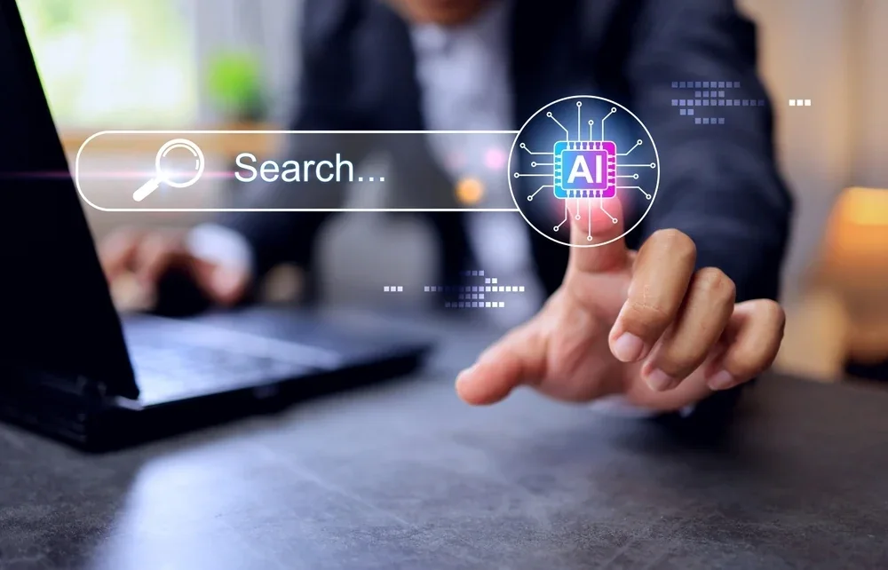Person tapping an AI-powered search bar on a laptop