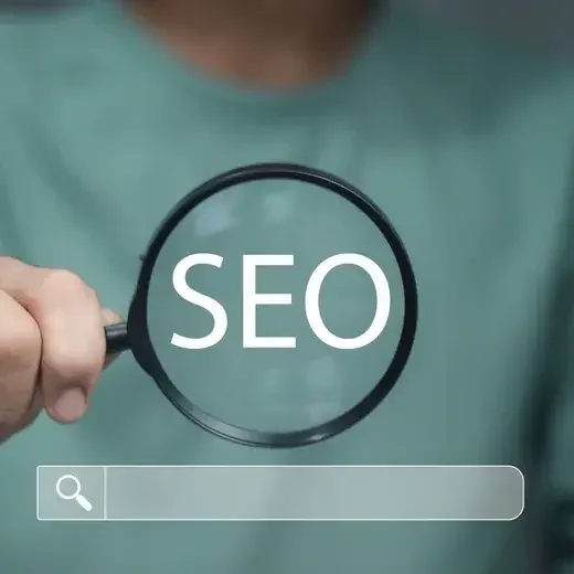 Person holding a magnifying glass over the word SEO above a search bar