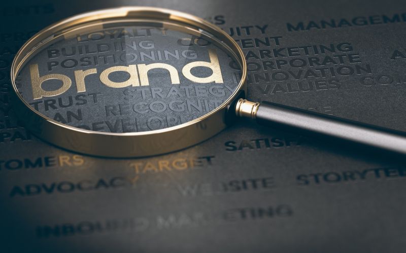 magnifying glass over the word "brand" to signify the importance of creating a brand that stands out