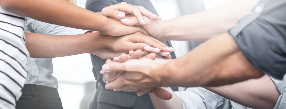 Team putting their hands together to demonstrate they have a culture in which they are close and connected to the work they do