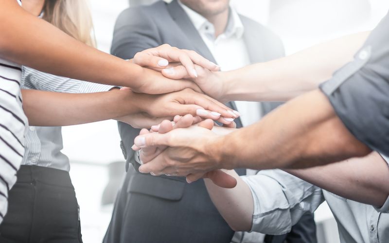 Team putting their hands together to demonstrate they have a culture in which they are close and connected to the work they do