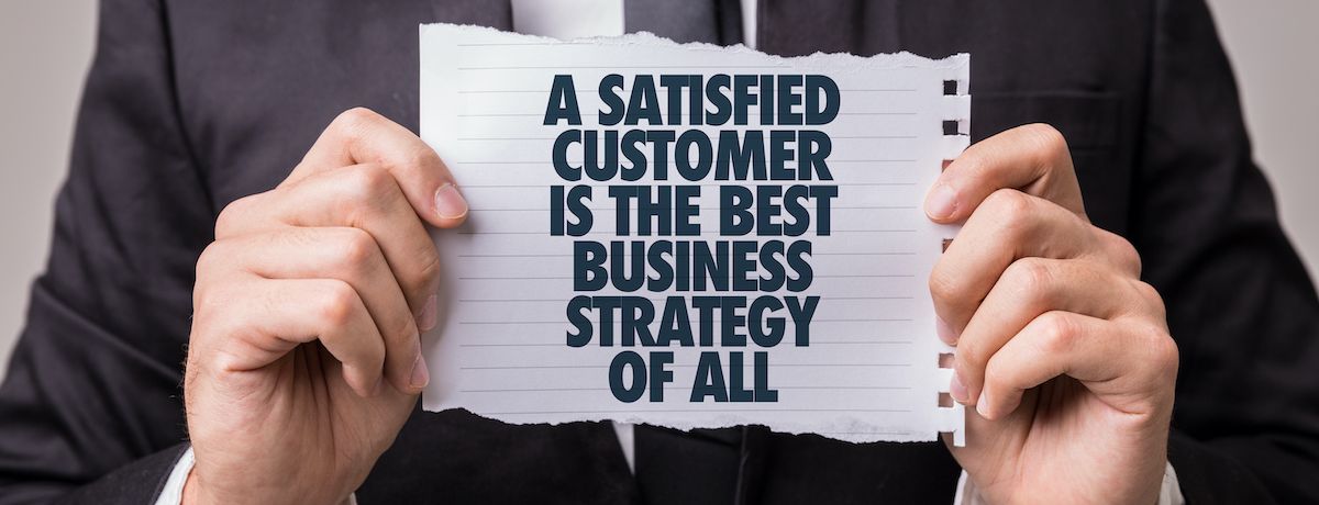 Business owner holding a sign that says a satisfied customer is the best business strategy
