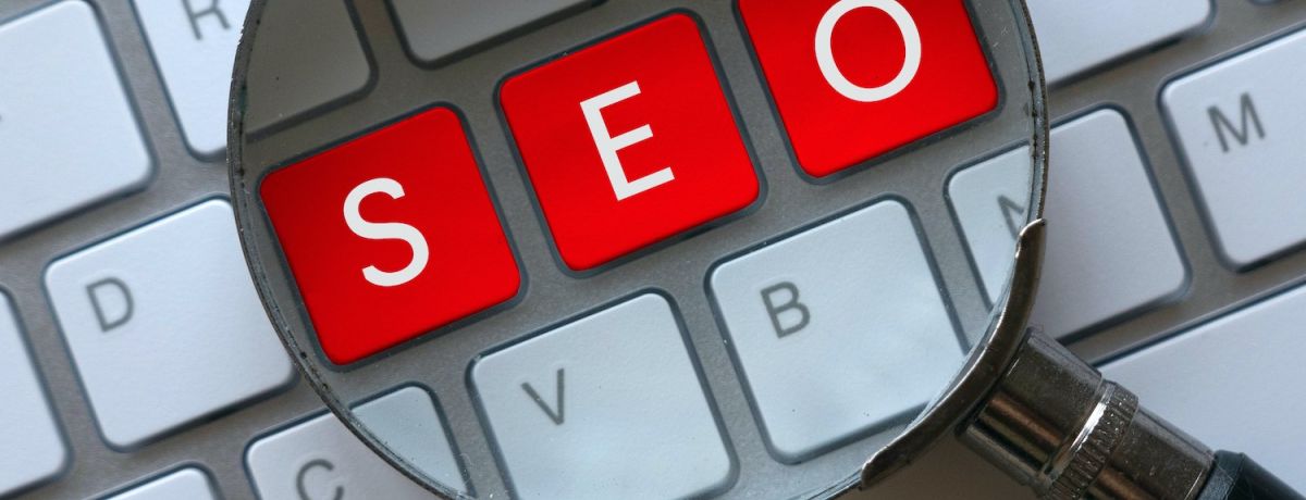SEO written on a keyboard with a magnifying glass on top to symbolize search