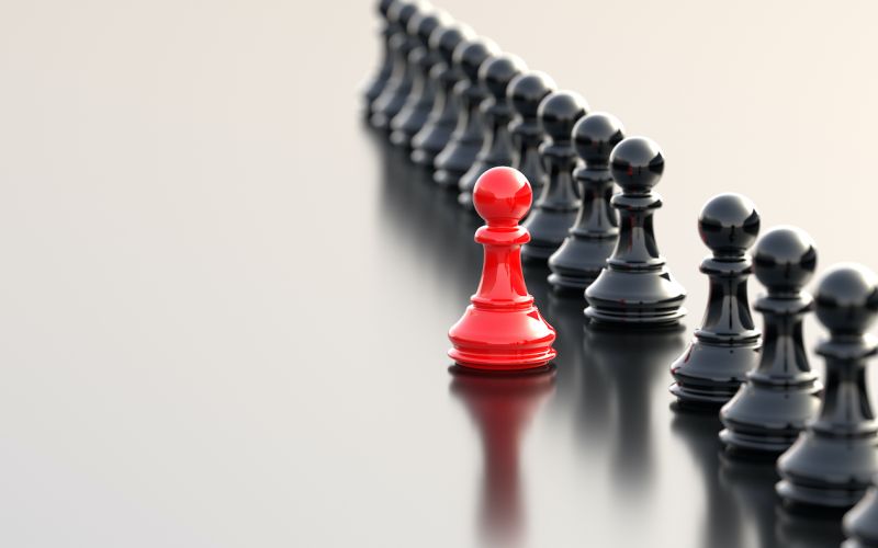 red chess piece standing out from black chess pieces to symbolize standing out from your houston business competition