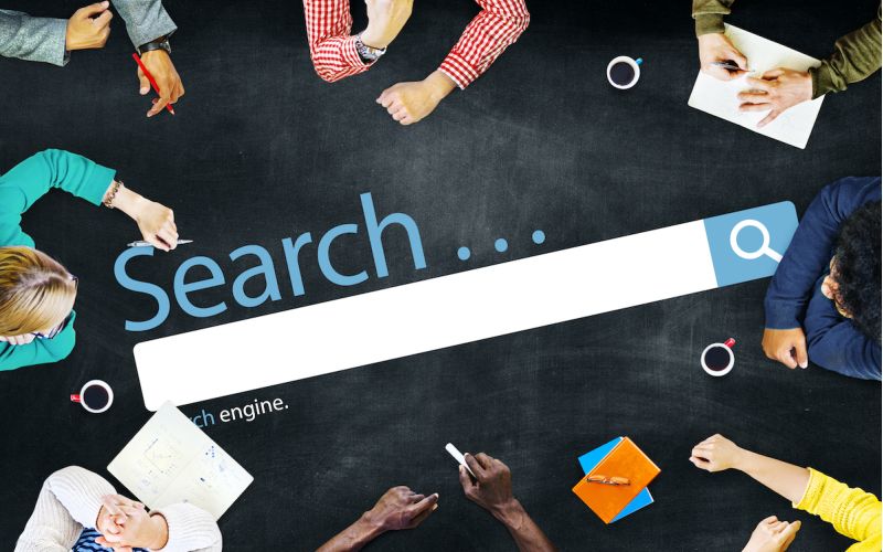 houston marketing professionals sitting at a table with a SEO search bar graphic in the middle